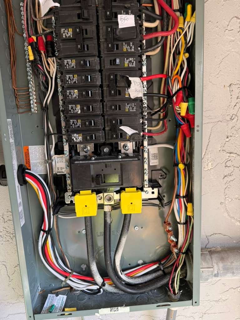 Close-up of an electrical panel with circuit breakers and wiring. The panel appears to have been recently worked on due to the cleanliness and organization of the wires.