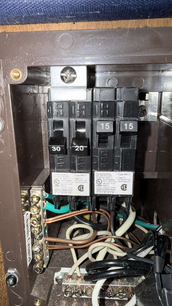 Photo of an electrical panel with multiple breakers and wiring. The panel includes 30 amp, 20 amp, and 15 amp breakers. Wiring is connected to a chassis ground.