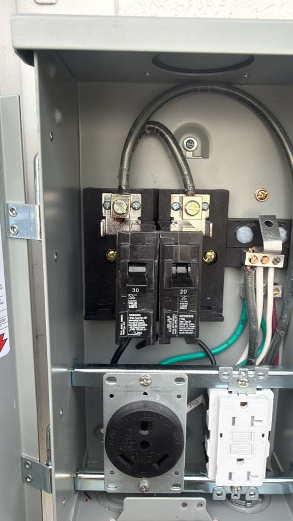 Electrical panel with circuit breakers for a generator or transfer switch installation, including a 30 amp and 20 amp breaker, a 240V outlet, and a GFCI outlet.