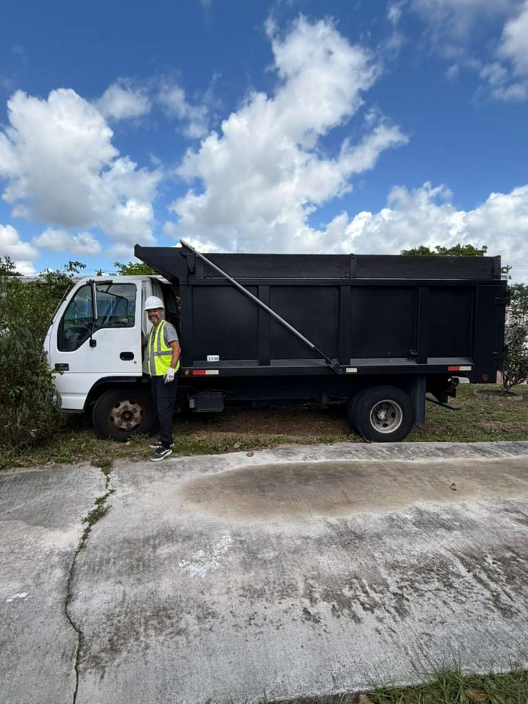 A man standing next to a dump truck, likely for debris removal from a demolition site.