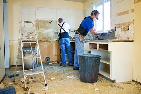 kitchen demolition with two workers and debris on the floor