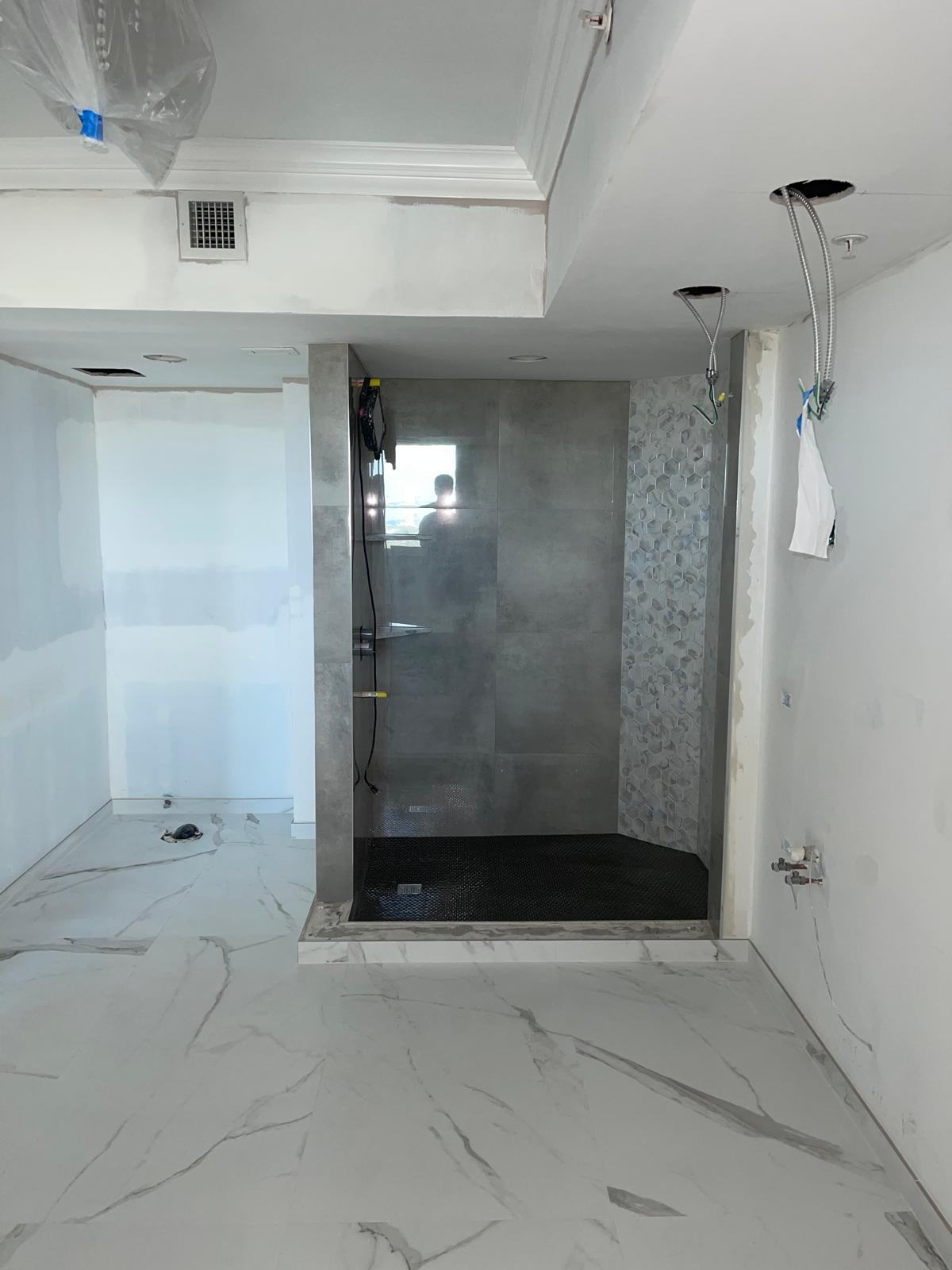 Open-concept shower build with porcelain slab flooring