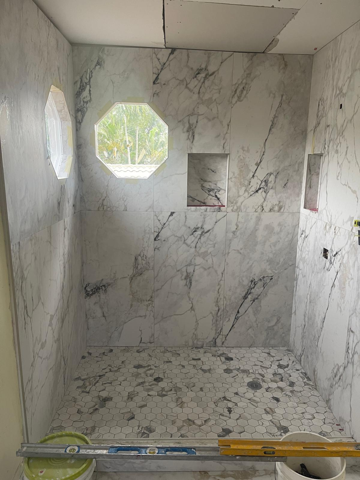 Marble-look shower with hex mosaic floor and niches