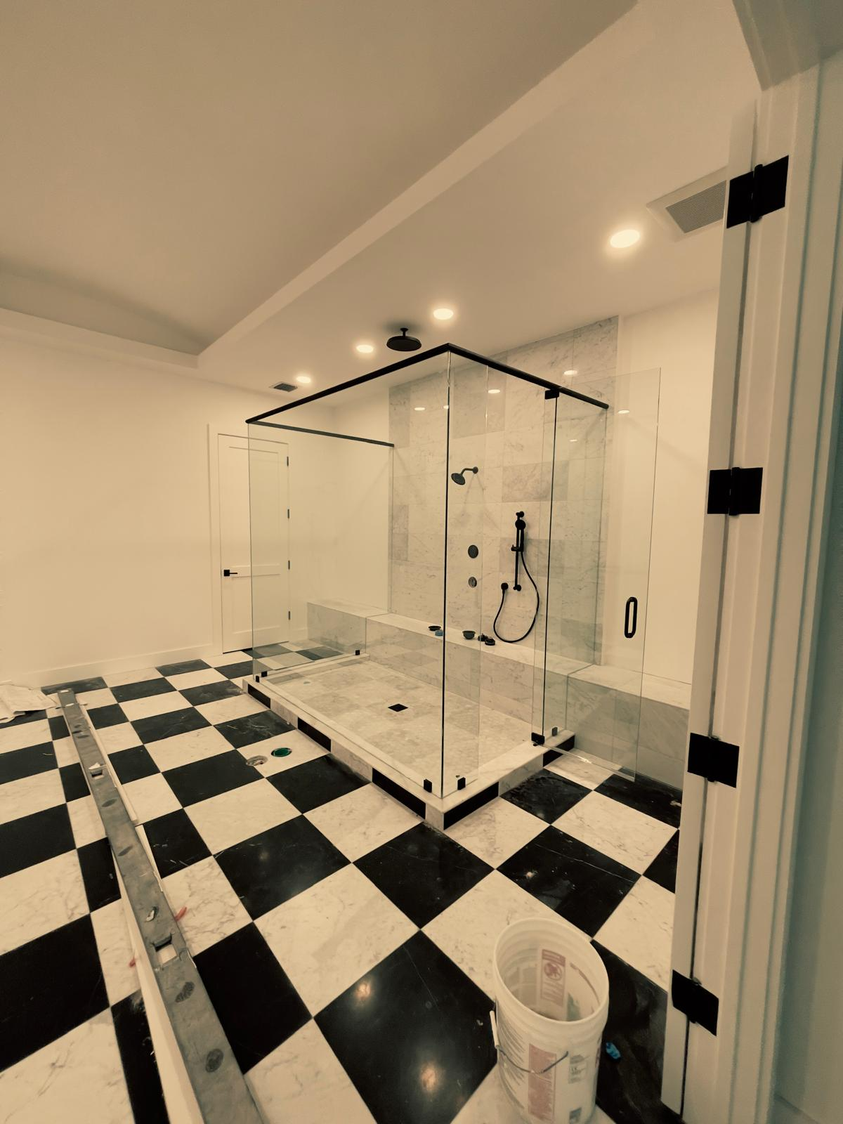 Glass enclosed shower with checkered marble floor